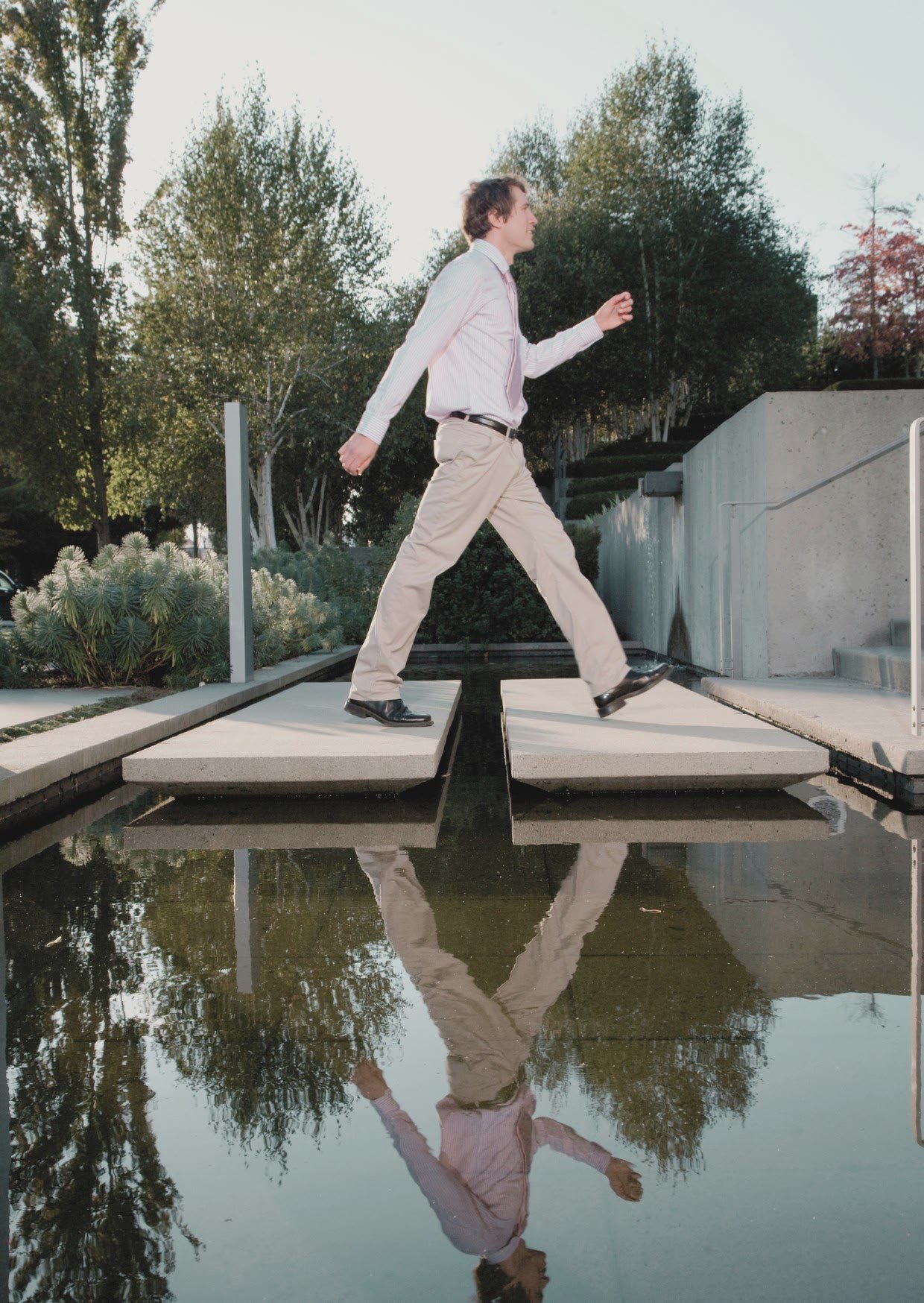 A man walking across stepping stones over water