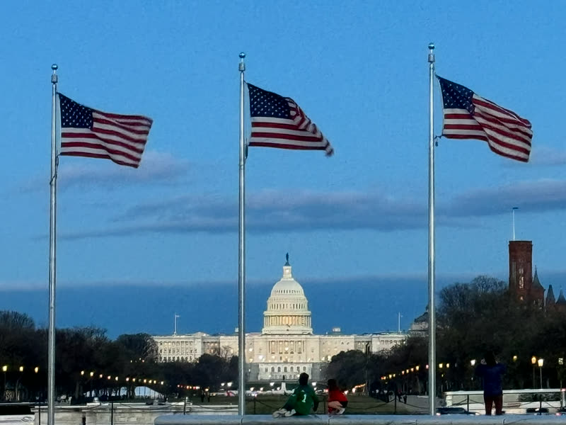 The United States Capitol behind three American flags